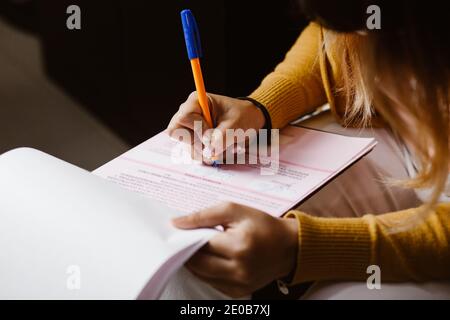 Latin woman hands writing and signing a document or a questionnaire in South America Stock Photo