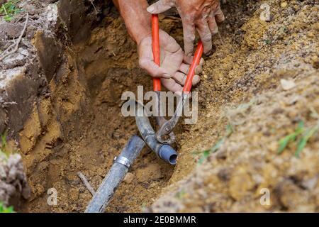 Underground sprinkler system to water the ground in man working with pipes in ground while installing Stock Photo