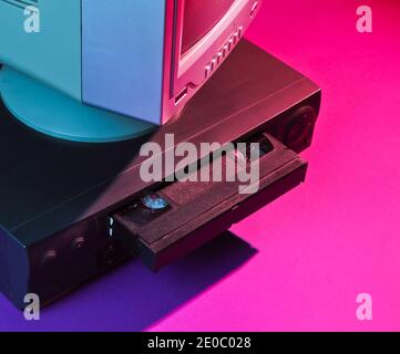 Retro wave, 80s concept. Video player with vhs cassette, old tv, neon light. Stock Photo