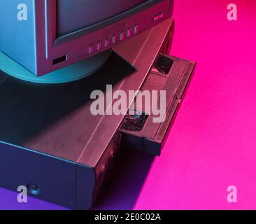 Retro wave, 80s concept. Video player with vhs cassette, old tv, neon light. Stock Photo