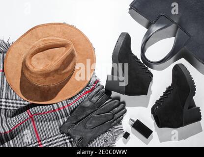 Autumn wardrobe. Women's things, shoes and accessories on a white background. Felt hat, suede boots, bag, leather gloves, bottle of perfume, scarf. Fl Stock Photo