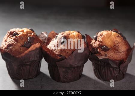 three Chocolate muffins on a dark background. Stock Photo