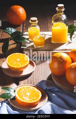 Oranges, oranges slices, orange leaves, and glass containers with orange juice on wooden background. Stock Photo