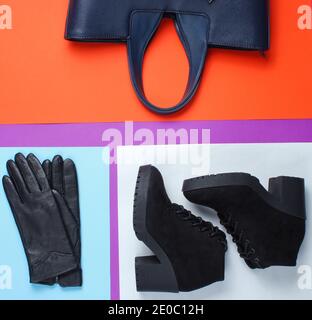 Women's accessories and shoes on a creative color paper background. Leather bag, gloves, suede shoes. Top view Stock Photo