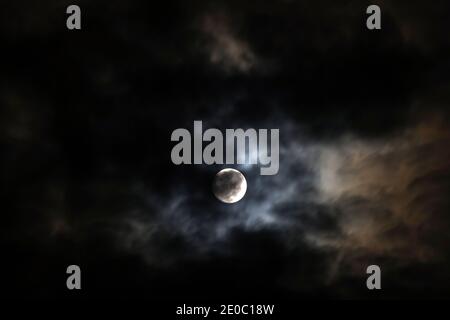 The Moon behind the clouds. The moon in a partially clouded colorful sky. Stock Photo
