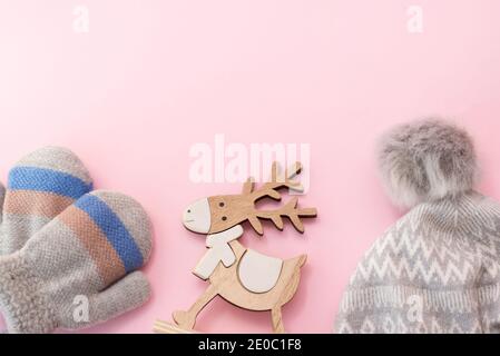 Baby winter clothes hat and mittens on pink background with wood toy deer, copy space. christmas holiday Stock Photo