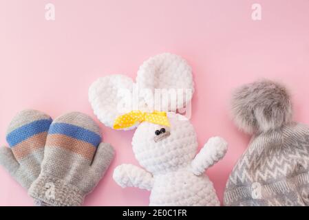 Baby winter clothes and toy on pink background, copy space Stock Photo