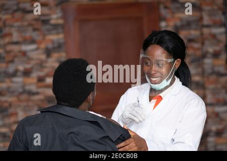 female medical practitioner smiling with a patient who is about to receive a vaccine shot Stock Photo