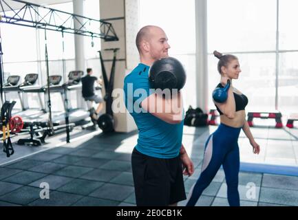 Сouple functional training. Sporty man and fit woman doing exercise with kettlebell in gym Stock Photo