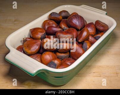 Closeup POV shot of sweet, raw, Spanish chestnuts in a ceramic dish / bowl. Stock Photo