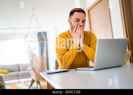 Upset young man counts family budget on laptop