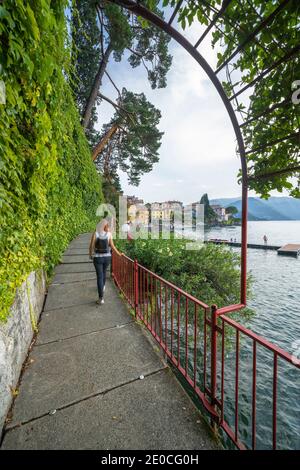 Woman walking on famous lovers' promenade on lakeside of Varenna, Lake Como, Lecco province, Lombardy, Italian Lakes, Italy, Europe Stock Photo