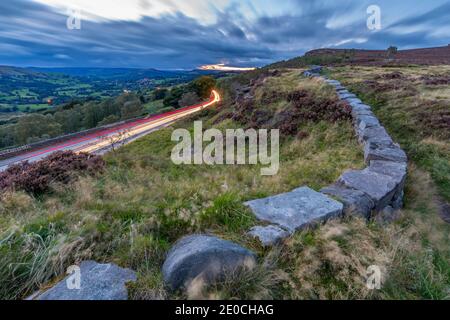 View traillights toward Hathersage from Lawrencefield during autumn, Hathersage, Hope Valley, Derbyshire Peak District, Derbyshire, England Stock Photo