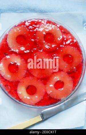 Cold cheesecake with raisins, pineapple and strawberry jelly Stock Photo