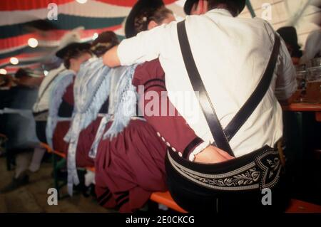 Germany /Bavaria /Munich/ Oktoberfest - coupel huging each other and the woman putting her hand in her boyfriend leather trousers. Stock Photo