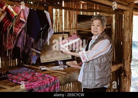 asian old elder woman elderly female showing traditional Thai fabric bag from Karen hill tribe in Northern Thailand Stock Photo