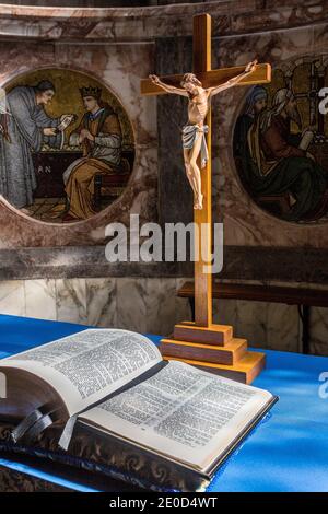 Statue of Jesus Christ on a cross with an open bible inside a church, depicting the crucifixion Stock Photo