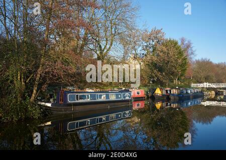 Narrowboats illuminated by the early morning winter sun along the Kennet  and Avon Canal near Bath in Somerset. Stock Photo