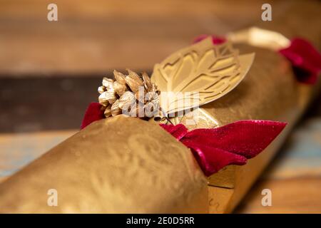 A classic British UK Christmas cracker with a golden acorn on a wooden table Stock Photo