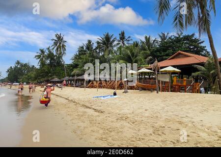 A woman wearing a traditional conical hat, called a Non La, selling fruit on the beach at Phu Quoc, Vietnam, Asia Stock Photo