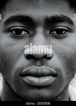 Close up of black and white of serious young African American hipster male with Afro hairstyle looking at camera Stock Photo