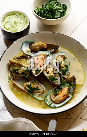 Cooked kiwi green mussels with wine, garlic and parsley served with baguette and butter with herbs Stock Photo