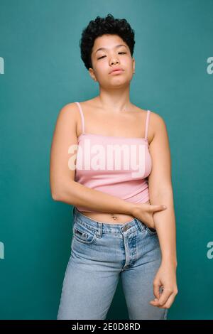 Young Latina Woman looking at the camera with her Asian eyes, American shot, isolated vertical photo, tidewater green background Stock Photo