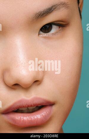 Crop of half face of beautiful Young Latina Woman, extreme close-up, isolated vertical photo, tidewater green background Stock Photo
