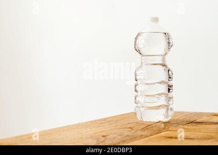 Transparent plastic bottle filled with fresh water placed on wooden table against white background Stock Photo