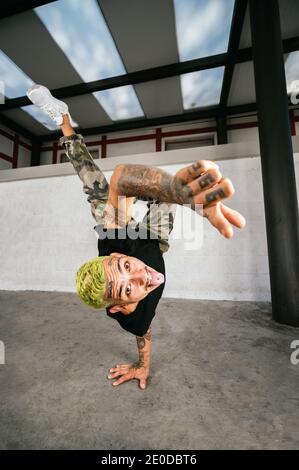 Full body of energetic young man doing acrobatic handstand while performing break dance Stock Photo