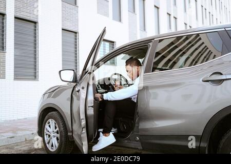Side view of African American male sitting in expensive car looking down Stock Photo