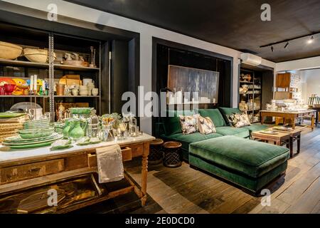 Stylish home interior design of lounge and dining areas in room with wooden floor furnished with green soft sofa and vintage wooden table setting with Stock Photo