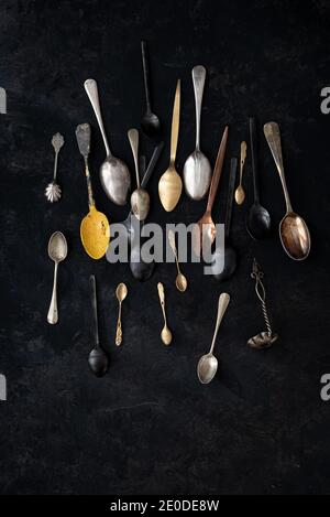 From above of set of various old fashioned spoons placed on black background in studio Stock Photo