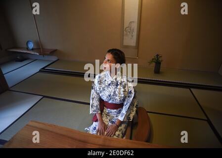 Young caucasian Woman in Japanese clothes sitting at the table in ryokan room and practicing mindfulness meditation Stock Photo