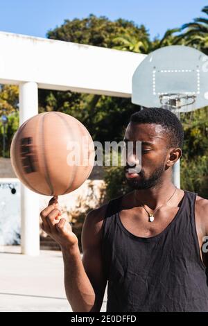 Determined African American male basketball player spinning and balancing ball on finger Stock Photo