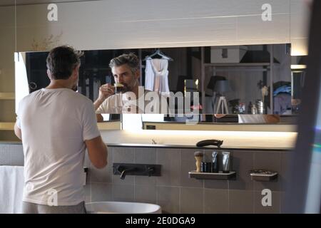 Stock photo of middle age man having a coffee and looking himself in the mirror. Stock Photo