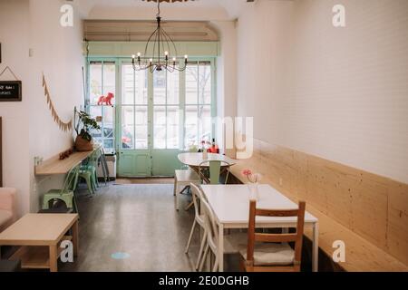 Cozy interior of confectionery cafe with simple furniture and vintage lamp in light room with old fashioned door Stock Photo