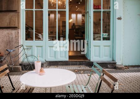 Yummy cupcake and glass of drink served on round table placed on terrace of cozy confectionery cafe Stock Photo