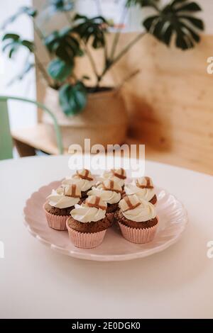 Delectable chocolate cupcakes with whipped cream on plate placed on table Stock Photo