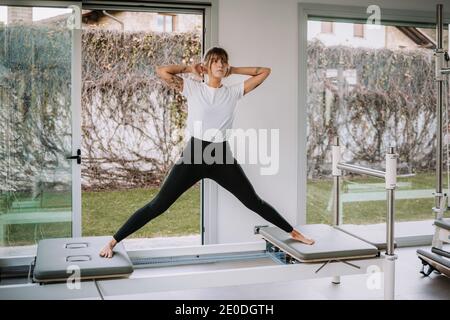 Slim female in activewear doing yoga in Warrior pose on pilates