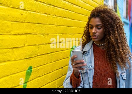 Reflection of pensive ethnic female in casual outfit with long hair and bright lips looking in mirror Stock Photo