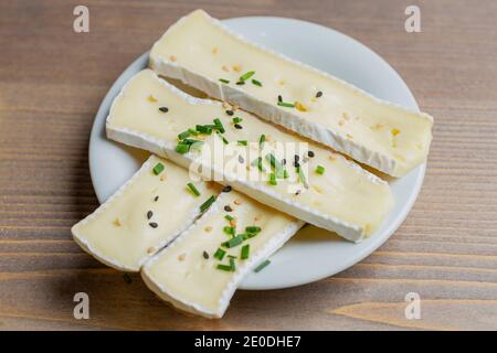 Brie cheese slices on white plate Stock Photo