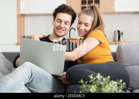 Couple using fast home internet with laptop. Woman and man on sofa in living room Stock Photo
