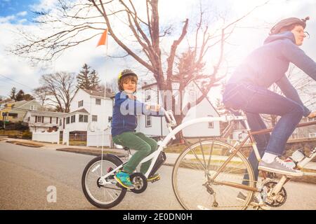 Portrait of a little boy ride on a tow tandem bike attached to father on urban street view from side Stock Photo