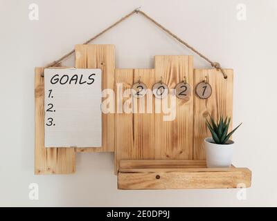 2021 plan notebook concept, hand writting notepad. Goals text on notebook. Close up, top view, glass, home plant, concept of planning, goal, action. Stock Photo