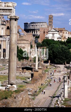 View of Roman Forum from Portico Dei Consentes looking down Via Sacra towards Coliseum. Temple of Saturn at left. Rome, Italy. Stock Photo