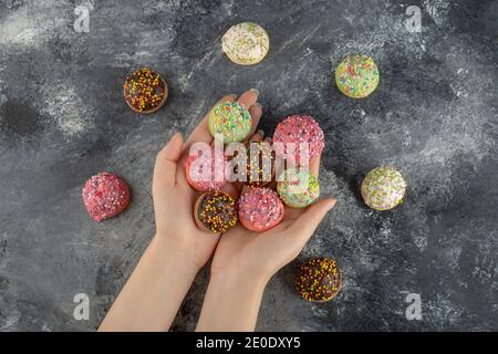 Hands holding colorful sweet small doughnuts with sprinkles Stock Photo