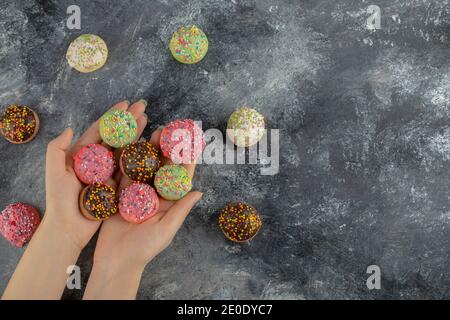 Hands holding colorful sweet small doughnuts with sprinkles Stock Photo