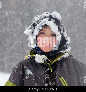 Portrait of a young boy (8 yr old) outside in falling snow in Quebec, Canada