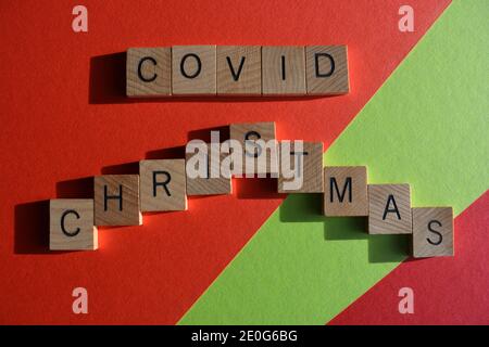 Covid Christmas, words in wooden alphabet letters isolated on red and green background Stock Photo